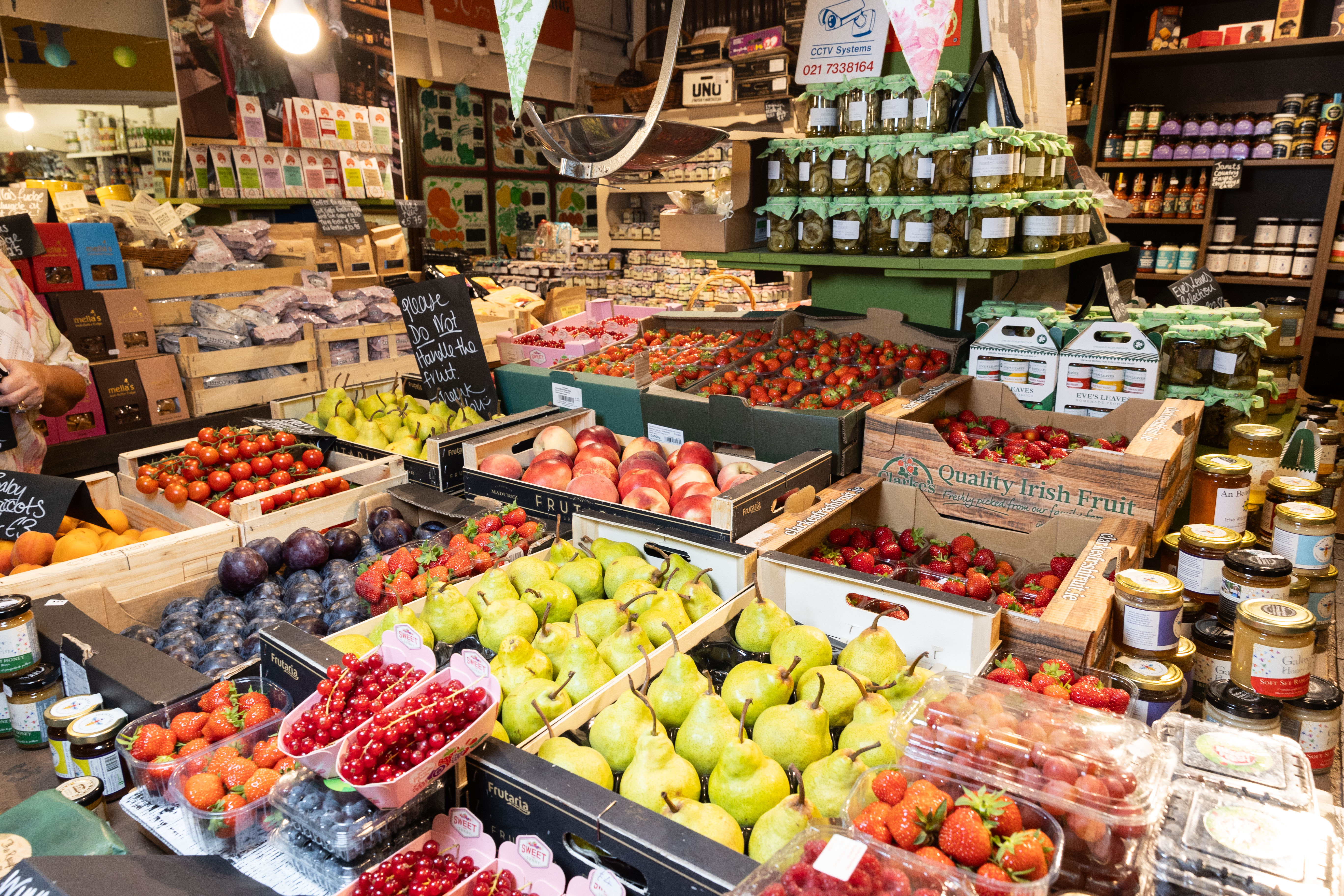 Crates of fresh fruit, berries, pears, tomatoes and jars of preserves at a produce stall inside the English Market in Cork.